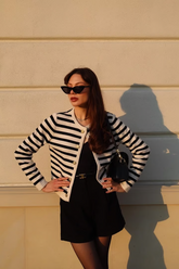 a lady in a black jumpsuit with a belt and a striped cardigan